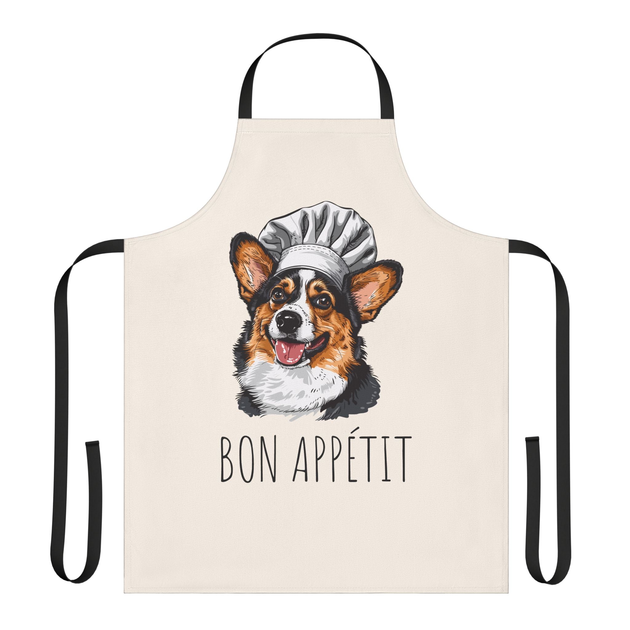 A cream-colored kitchen apron with black neck and waist straps, featuring a printed illustration of a corgi dog wearing a white chef's hat above the French text 'BON APPÉTIT'.